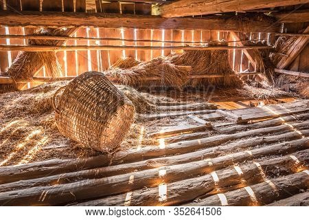 Early Morning Sunlight Streams Into A Rustic Barn On Broken Basket Nex To Pile Of Hay. Nice Rustic V