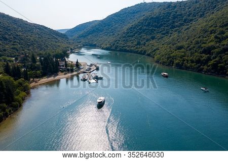 A Narrow Water Bay Of Karst Origin In A Mountainous Area. There Is A Pier With Boats On The Bank Of 