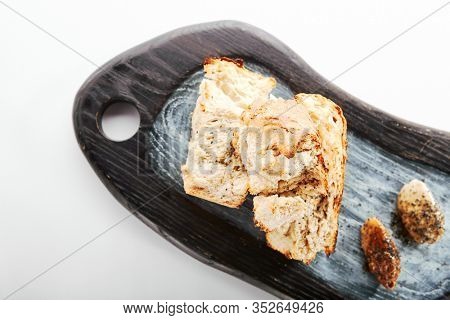 Burnt ciabatta with two kinds of butter. Aromatic fresh bread on wooden cutting board. Delicious rustic meal and cooking utensil. Traditional italian dish. Food presentation, pastry on white surface