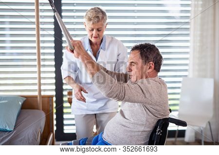 A Healthcare Worker Helping Paralysed Senior Patient In Hospital.