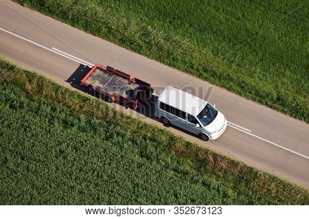 Aerial View Of White Van Carrying A Trailer For A Hot-air Balloon Basket In A Beautiful Green Landsc