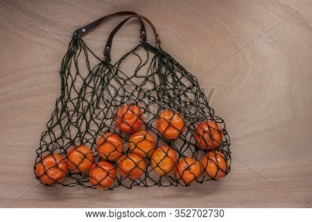 Mandarins In Green Net Bag Zero Waste Concept Lay On Wooden Table
