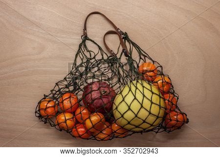 Mandarins, Pomelo, Pomegranate In Green Net Bag Zero Waste Concept Lay On Wooden Table