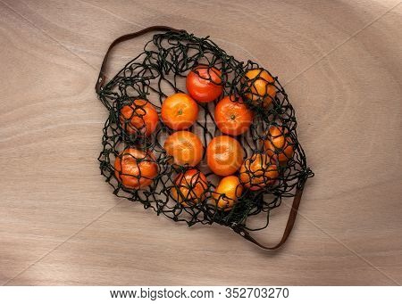 Mandarins In Green Net Bag Zero Waste Concept Lay On Wooden Table