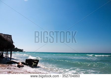Panoramic View Of Playa Blanca On Baru Island, Cartagena, With Tree Trunk On The Beach.