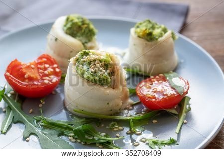 Three Fish Fillet Rolls From Plaice Filled With Mashed Celery And Arugula, Served With Grilled Tomat