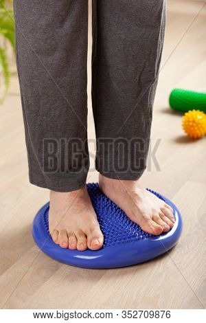 man doing flatfoot correction gymnastic exercise balancing on massage cushion at home