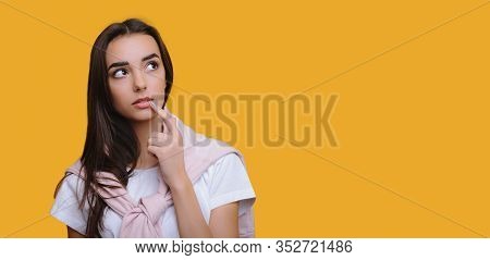 Caucasian Girl Touching Her Lips While Thinking About Something And Posing On A Yellow Background Wi