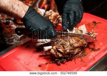 Chev Cuts Juicy Cooked Meat, Separating The Meat From The Bone With A Knife.