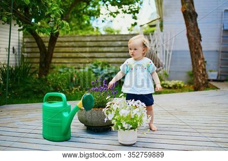 Cute Baby Girl Playing With Watering Pot A Warm Summer Day. Little Kid Helping Parents To Take Care 