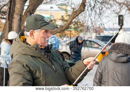 Petrozavodsk, Russia - 9 February 2020. Elderly Man Makes Selfie With Help Of Selfie Sticks