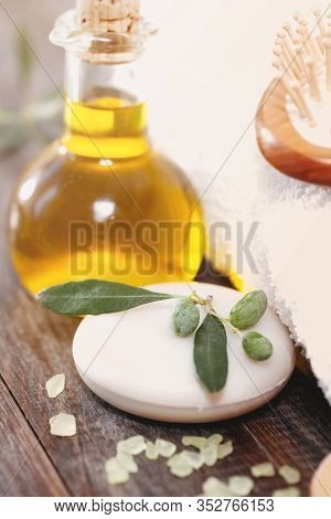 Soft Towel Placed On Lumber Table Near Fresh Olive Oil And Salt In Spa Salon