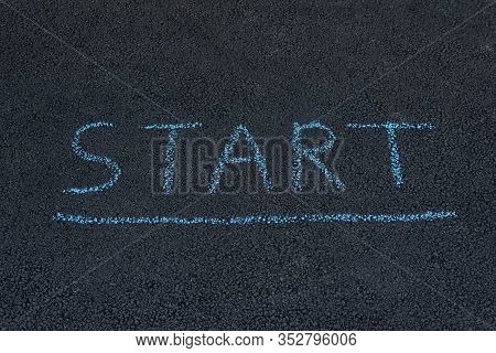 Text Start Underfoot. Texture Road Surface. Black Asphalt With Chalk Inscription