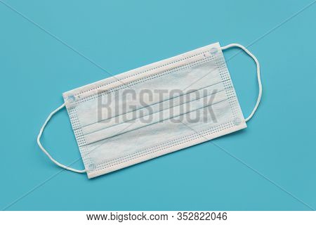 Surgical Ear-loop Mask On Blue Background. Top View. Protection Concept