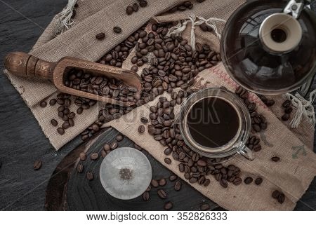 Coffee Style, Cup Of Coffee And Coffee Beans Roating With Old Wooden Scoop And Coffee Beans Around O
