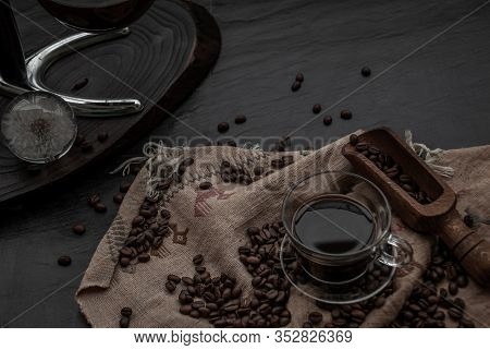 Coffee Style, Cup Of Coffee And Coffee Beans Roating With Old Wooden Scoop And Coffee Beans Around O