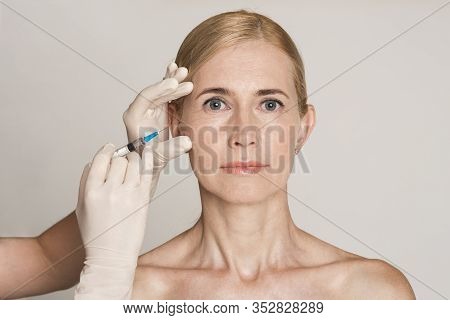 Plastic Surgery. Blonde Middle-aged Woman Receiving Botox Injection In Beauty Clinic Isolated On Gra