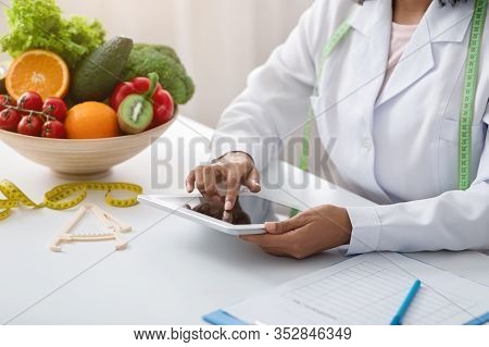 Cropped Of Dietologist Black Woman Using Digital Tablet At Workplace