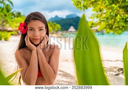 Asian beauty model with healthy glowing skin sun tan body care skincare concept. Woman portrait wearing bikini on beach.