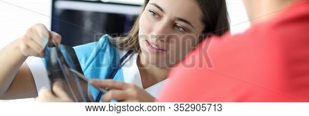 Portrait Of Serious Doctor Discussing Diagnosis On Skiagram With Ill Client. Professional Traumatolo