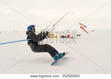 A Male Athlete Engaged In Snow Kiting On The Ice Of A Large Snowy Lake. He Goes Skiing In The Snow. 