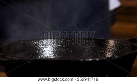 Close Up Of Male Chef Frying Ingredients In Black Iron Pan And Stirring Them With A Metal Shovel. St