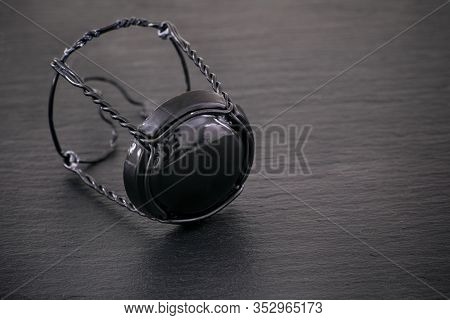 Champagne Muselet With Black Cap On Black Stone Background. Close-up