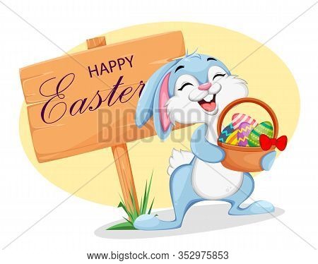 Easter Rabbit Stands Near Wooden Sign And Holds A Basket Of Eggs. Greeting Card With Funny Easter Bu