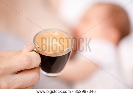 Mother breastfeeding newborn baby while drinking coffee. Breastfeeding and caffeine consumption concept