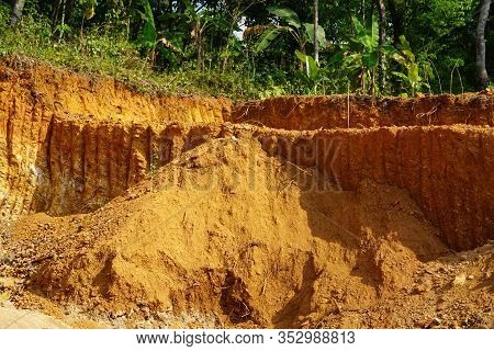 Deforestation Close Up With Roots, Rocks Showing In Sunlight. Red And Yellow Rocks Where Soil Was Du