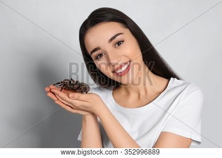 Woman Holding Striped Knee Tarantula On Light Background. Exotic Pet