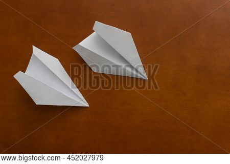 Two Paper Airplanes On A Wooden Office Desk