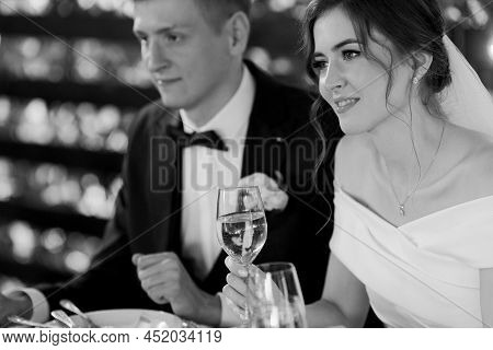 Newlyweds Sit At A Table In A Restaurant And Listen To Congratulations