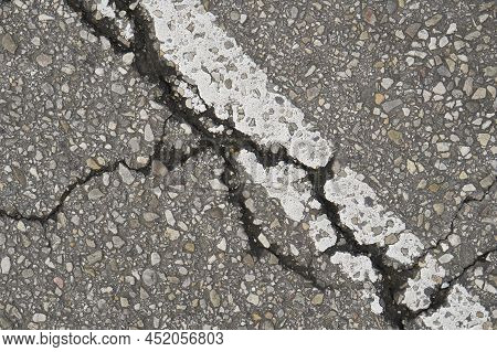 Old Damaged Cracked Asphalt Road Section With Old Paint Road Marking. Texture Damage. Deterioration