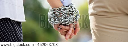 Rear View Of Couple's Hand Tied With Metal Chain At Outdoors