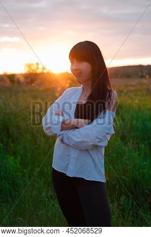 Young Woman In Baldric On The Summer Field On Sunset Or Sunrise. Peaceful Calm Female. Trendy Clothe