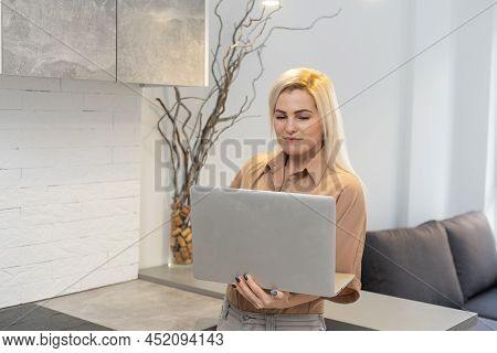 Nice Beautiful Blonde Lady Works At The Notebook Sit Down On The Sofa At Home - Check On Oline Shops