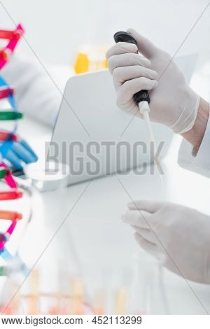 Cropped View Of Geneticist In Latex Gloves Holding Micropipette Near Blurred Laptop.