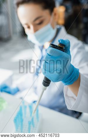 Blurred Geneticist In Medical Mask Working With Micropipette In Lab.