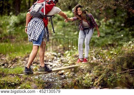 Young Cuople Crossing River.Journey in the forest