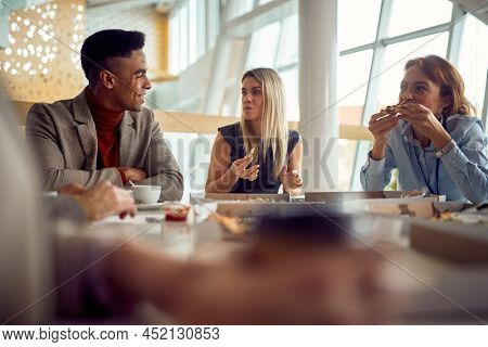A young business man is chatting with female colleagues during a lunch break in a pleasant atmopshere in the company building. Business, people, company