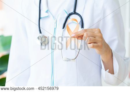 Close Up Of A Doctor Holding And Showing Orange Awareness Ribbon In Her Hands