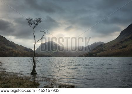 Stunning Autumn Sunrise Landscape Image Of Buttermere In Lake District With Dramatic Stormy Sky