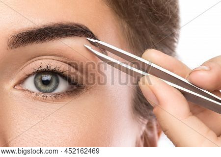 Close-up Of Female Face And Eyebrow With Tweezers