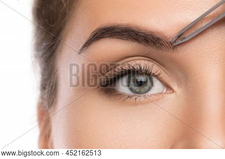 Close-up Of Female Face And Eyebrow With Tweezers