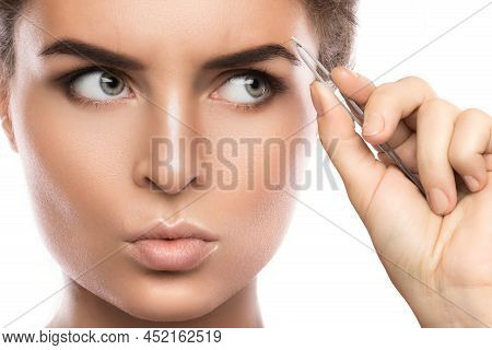 Close-up Of Female Face And Eyebrow With Tweezers