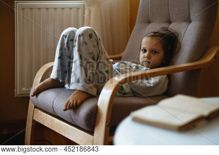Bored Sad Toddler Child Lonely At Home Sitting On Armchair. Sad Relaxed Candid Kid At Home In Cozy W