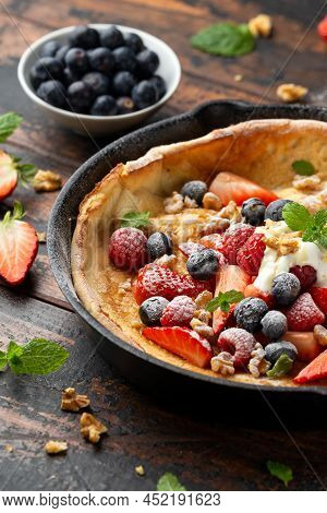 Dutch Baby Pancake With Berries And Icing Sugar In A Iron Cast Pan. Morning Breakfast