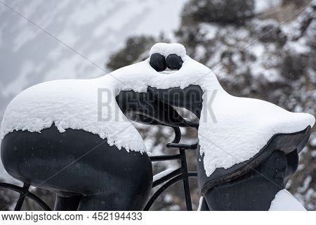 Escaldes Engordany, Andorra: 2022 April 2: Sculpture By Botero Cyclist And Woman Kiss. Whit Snowfall