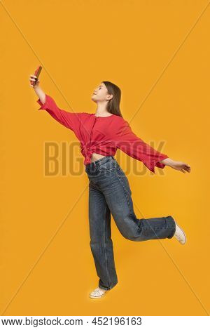 Young Girl Takes Selfie Or Shoots Stories For Social Networks. Portrait Of Teenage Girl In Red T-shi